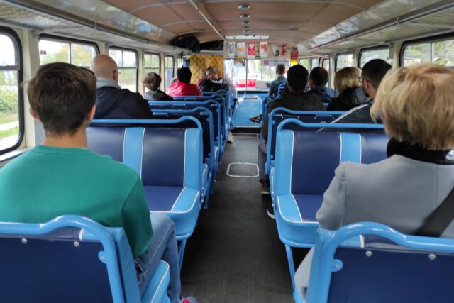 Pasażerowie na niebiesko-granatowych siedzeniach w autobusie San H100