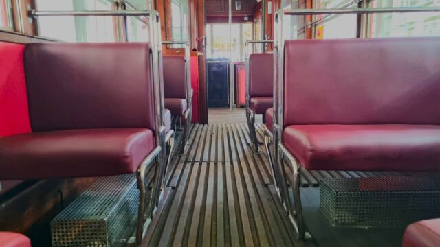 Wnętrze historycznego tramwaju (przeważa kolor wiśniowy)